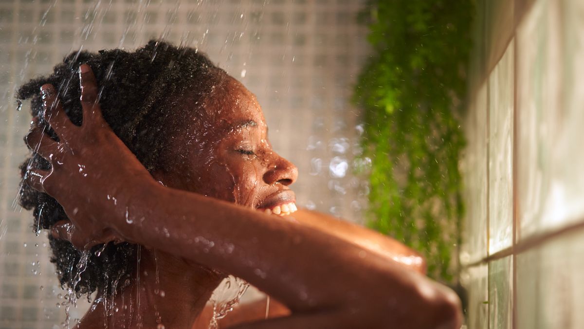 cheerful young woman taking a refreshing shower at home, washing her hair