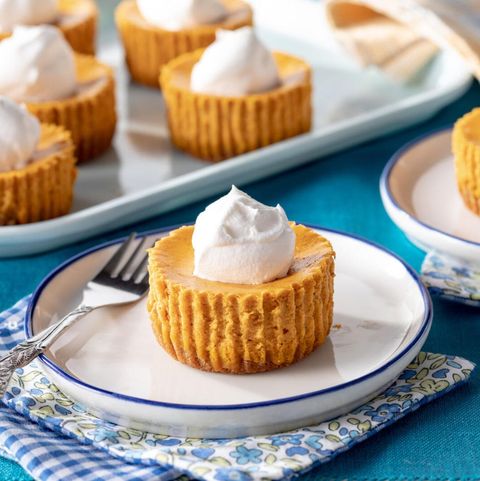 mini pumpkin cheesecakes on tray with one on white plate