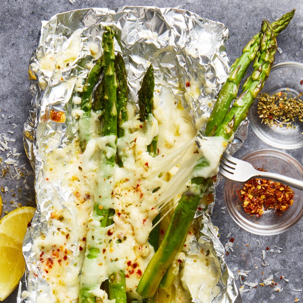 asparagus topped with cheese in foil packs topped with red pepper flakes