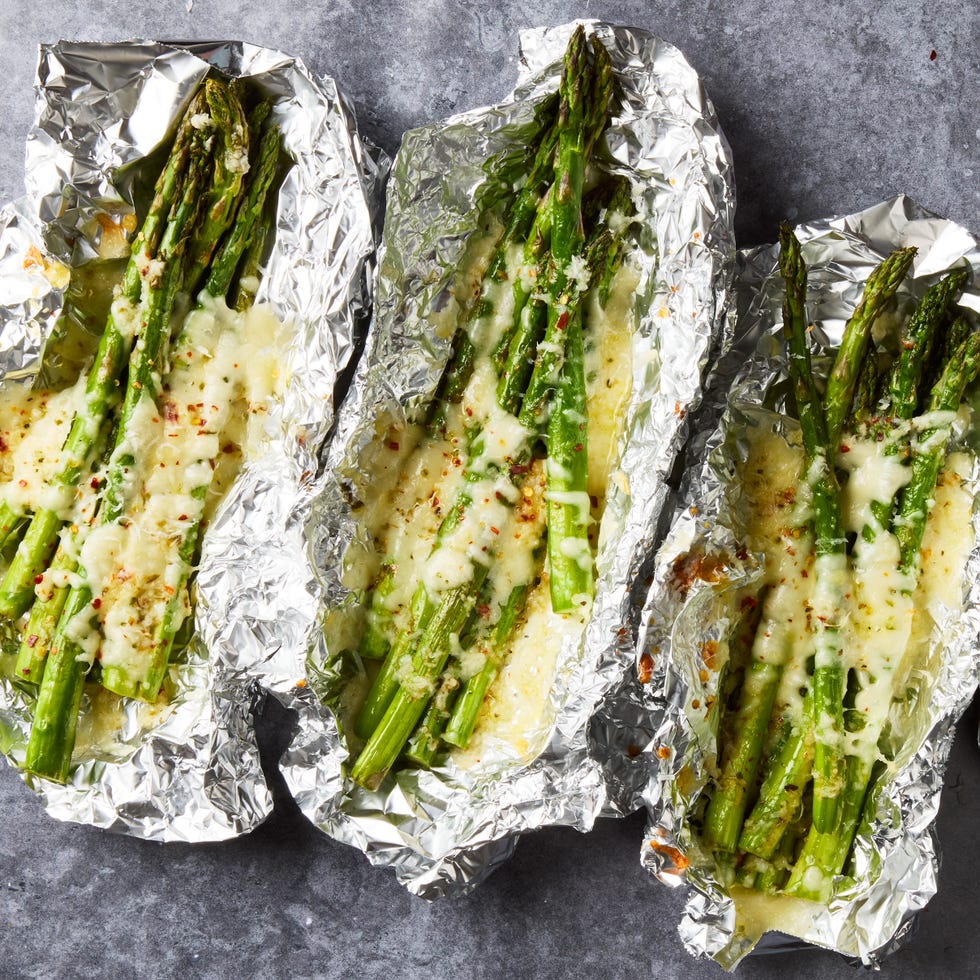 asparagus topped with cheese in foil packs topped with red pepper flakes