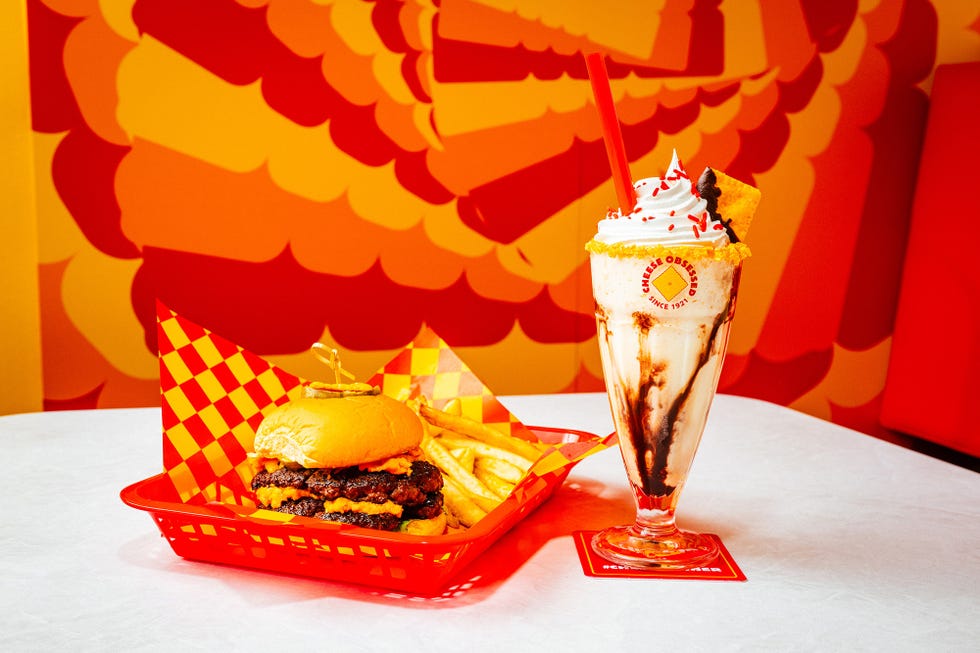 a glass of beer next to a burger and a drink