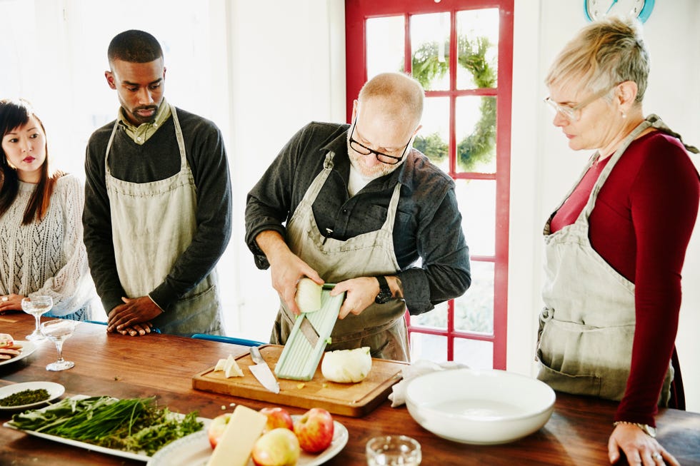 chef demonstrating how to use mandoline while teaching cooking class