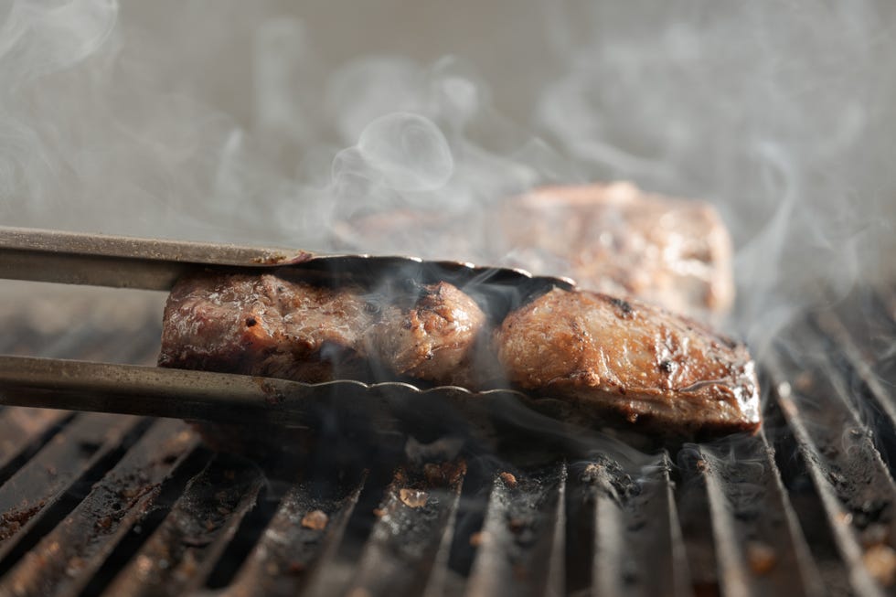chef grilling meat with sizzling smoke