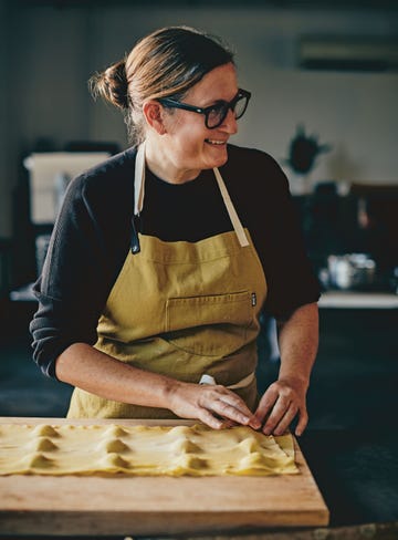 a person working with pasta dough on a wooden surface