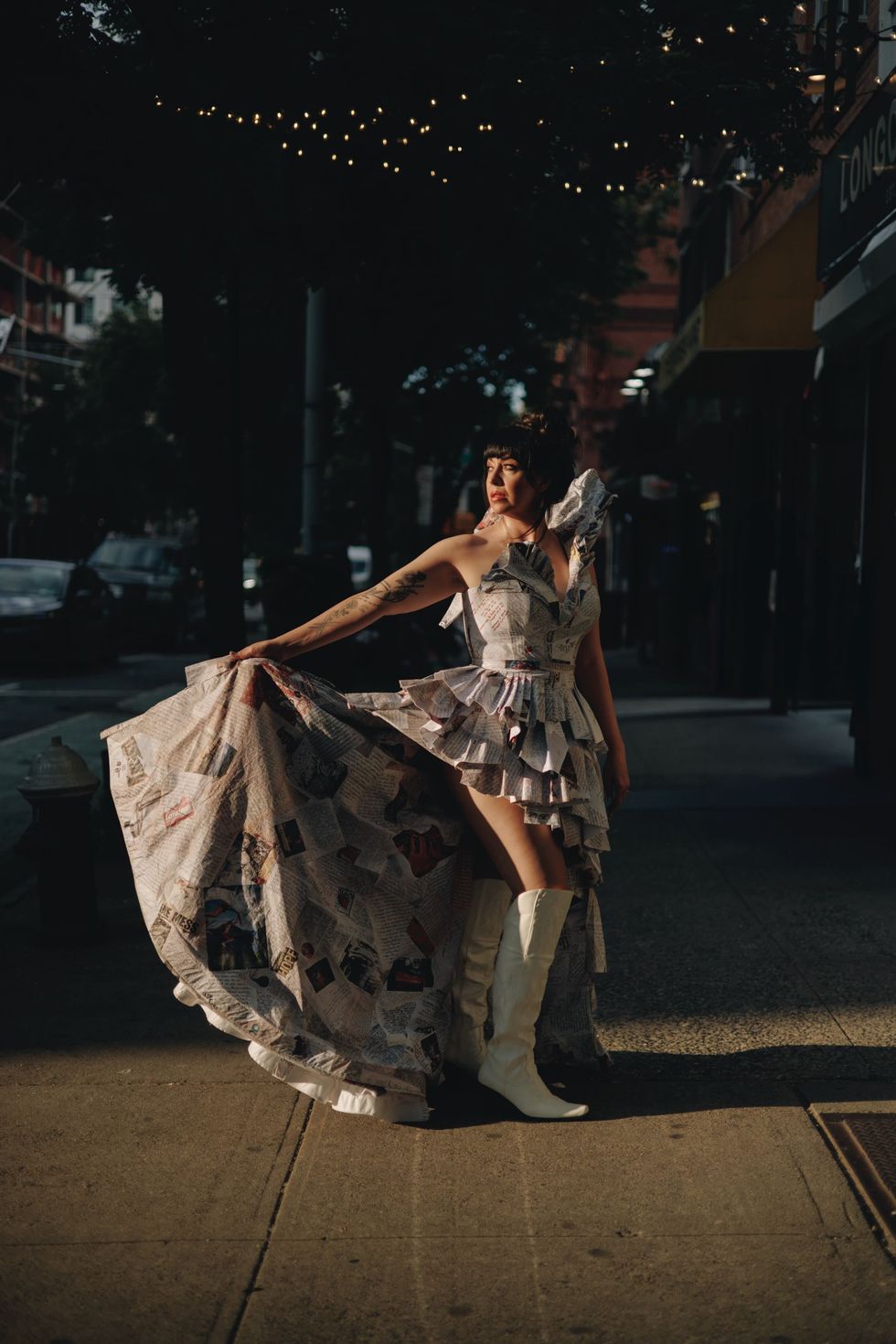 a person in a dress holding a large bag of trash on a street