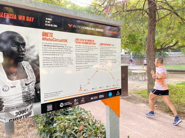 un hombre corre por el circuit 5k de valencia frente a la señal que marca los ritmos de cheptegei