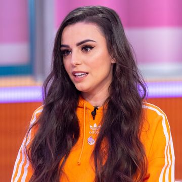 cher lloyd wears her long brown hair down over her shoulders and sports a bright orange sports jumper