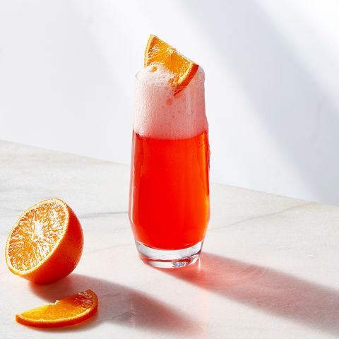 cherry bomb mimosa in a glass topped with an orange slice