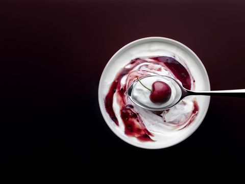 cherry yogurt with spoon and whole cherry on dark background
