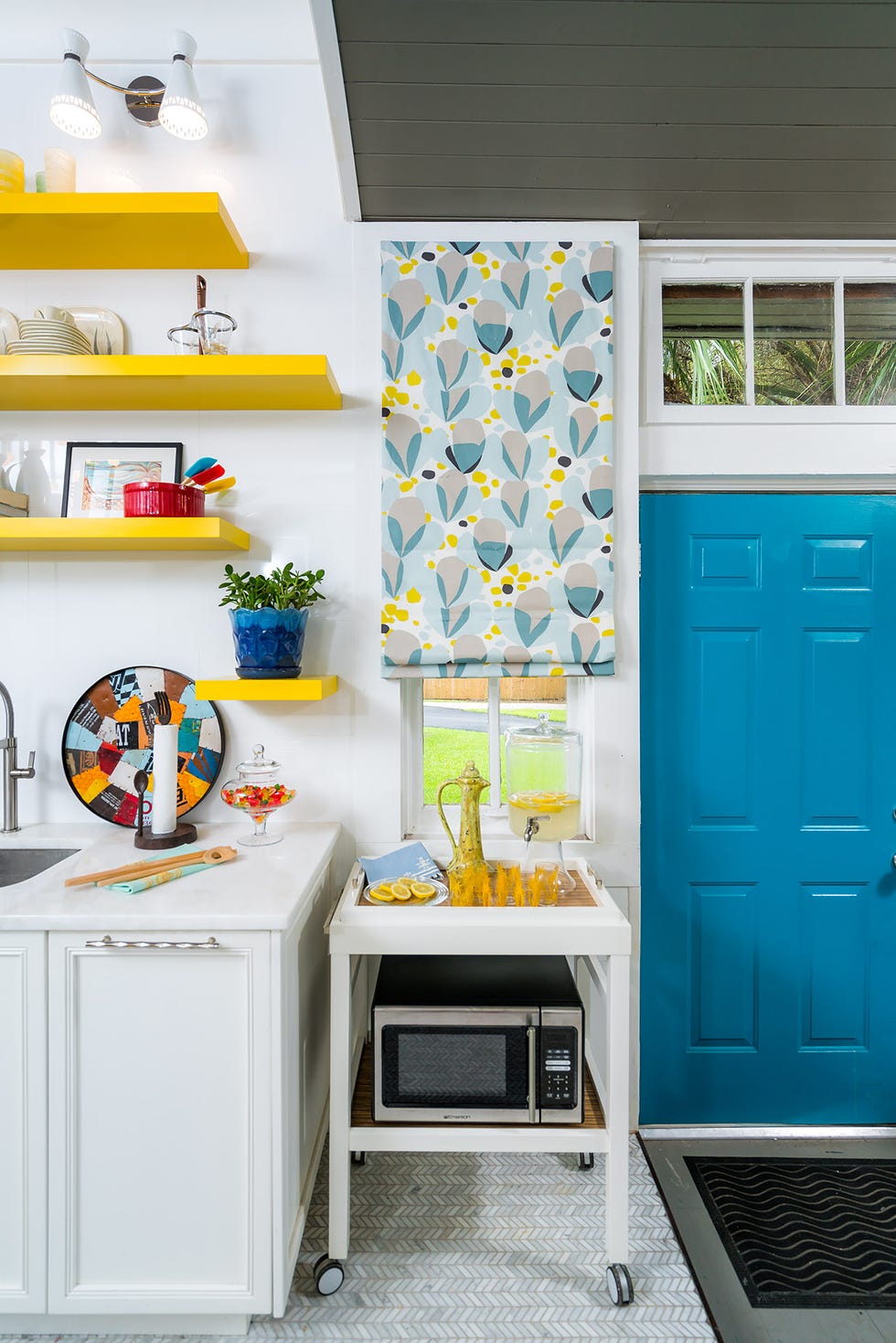 bright kitchen area featuring a serving cart with drinks colorful shelves and blue door