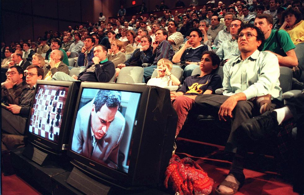 Chess fans watch in an auditorium progress of the