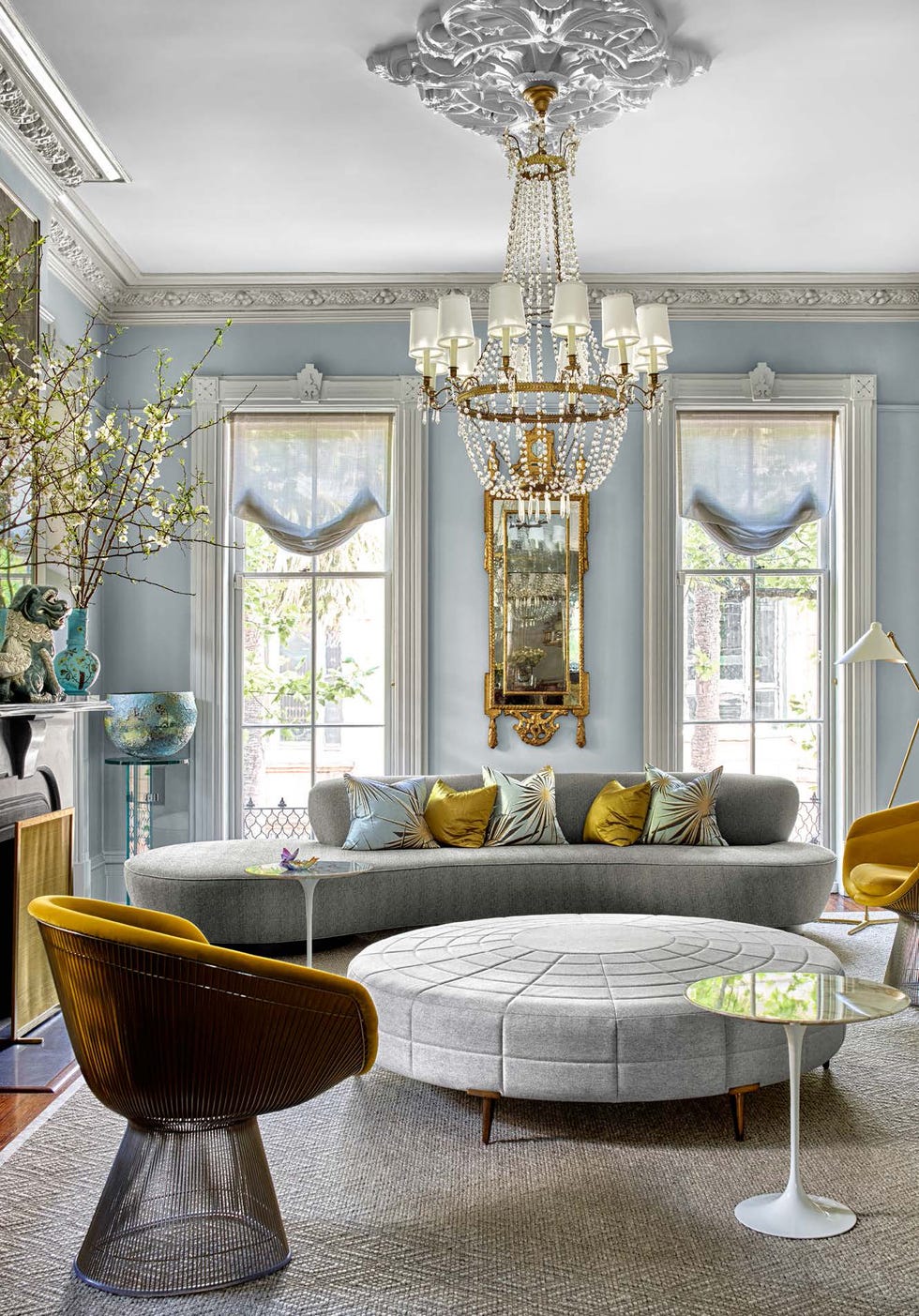 Long gray sofa with orange chairs and sheer curtains 