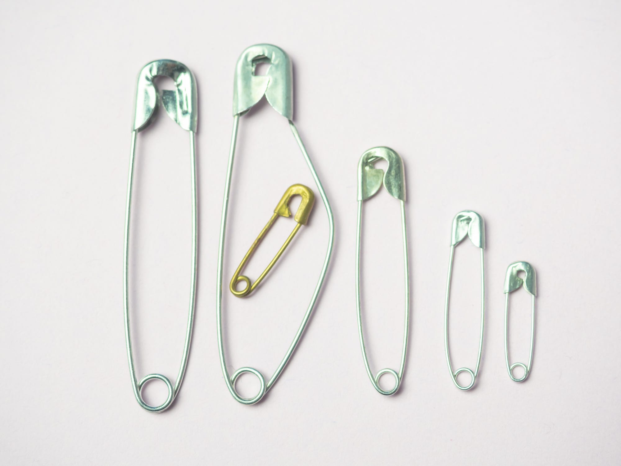 conceptual image with sewing safety pins on white background with space for text