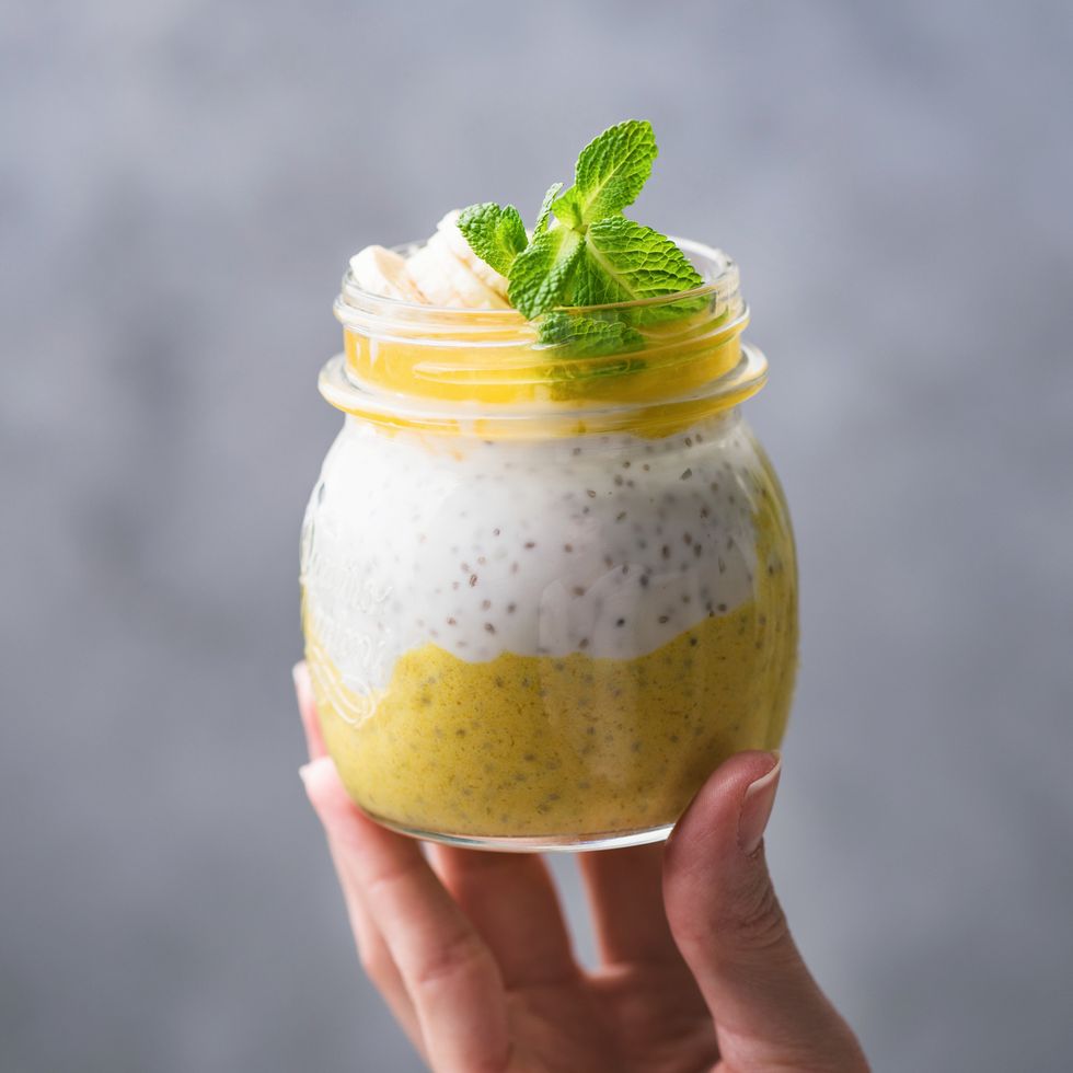 mango chia pudding in jar in girl hand healthy eating, healthy diet, vegan food concept