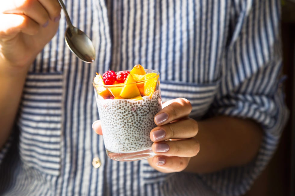 hands holding a jar of chia pudding with fruit