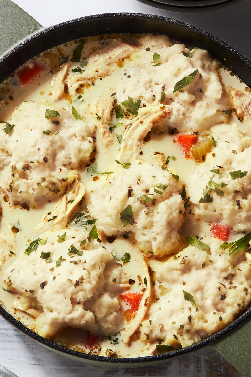 shredded chicken and dumplings and carrots in a creamy broth, topped with chopped parsley