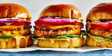 chicken burger topped with sauce, lettuce, sliced red onion, and tomato