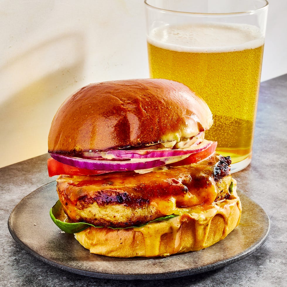 Chicken burger topped with sauce, lettuce, sliced ​​red onion and tomato