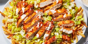 caesar salad topped with fried chicken pieces over fries