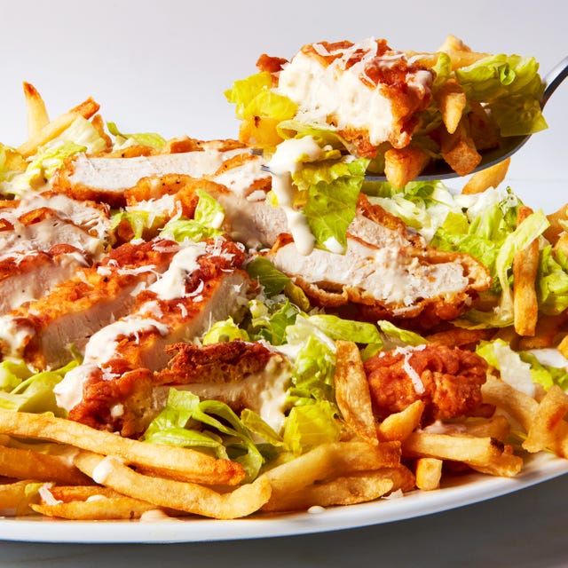 caesar salad topped with fried chicken pieces over fries