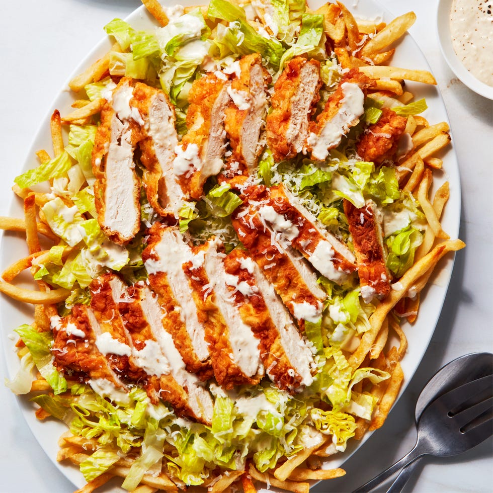 caesar salad topped with fried chicken pieces over fries