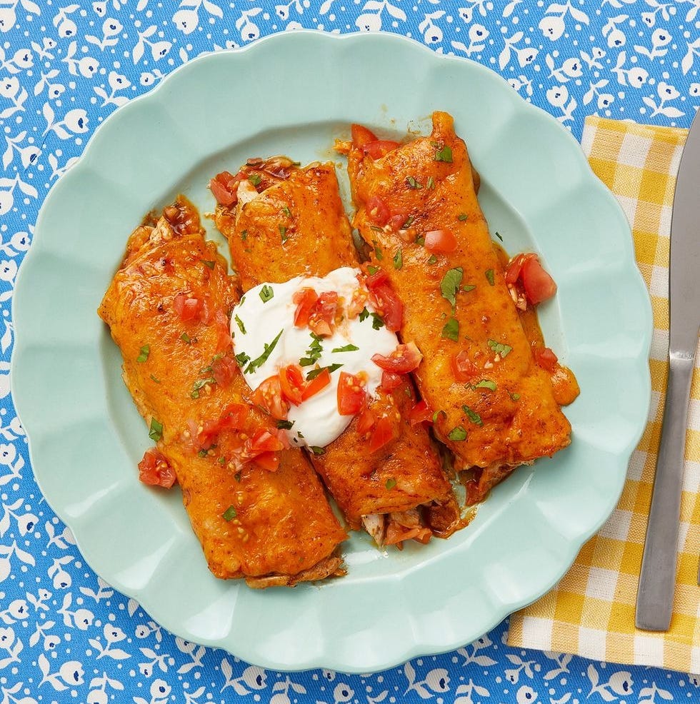 chicken enchiladas with red sauce and sour cream on plate