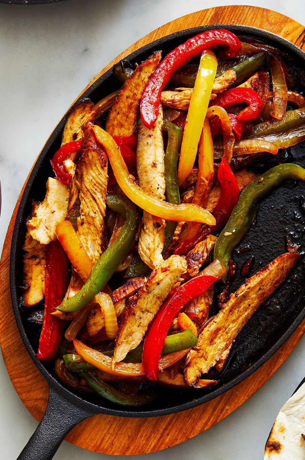 chicken fajitas on a steaming plate with peppers and onions
