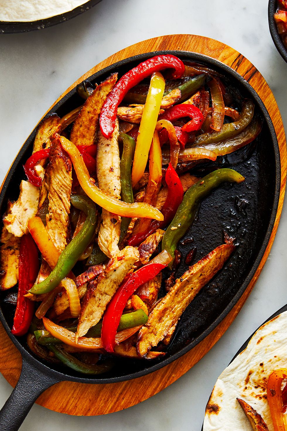 chicken fajitas on a steaming plate with peppers and onions
