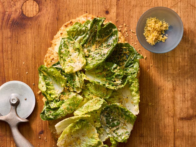 chicken pizza caesar salad a quote pizza made from ground chicken topped with caesar salad on a wooden board