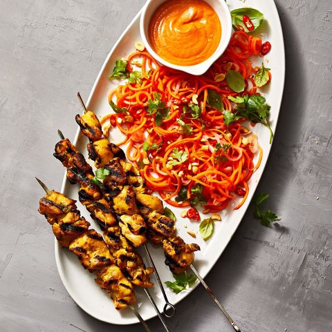 chicken satay with spiralized carrot salad on a white plate
