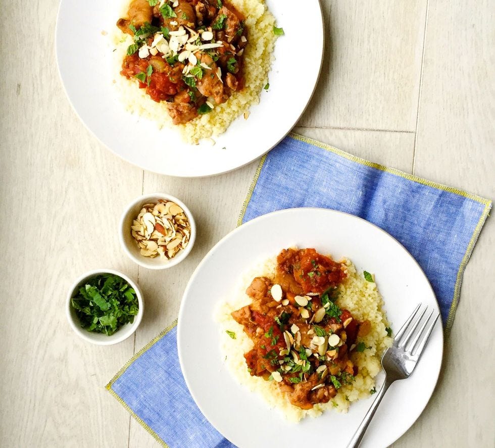 chicken tagine with sliced almonds and parsley over couscous on white plates