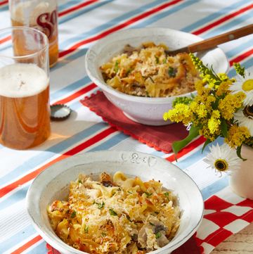 a table with bowls of chicken tetrazini and a glass of beer