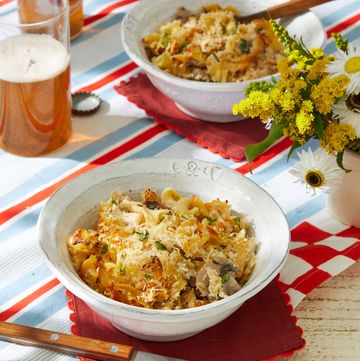 a table with bowls of chicken tetrazini and a glass of beer