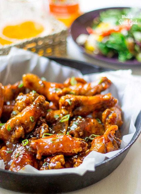 peach glazed chicken wings in bowl with paper