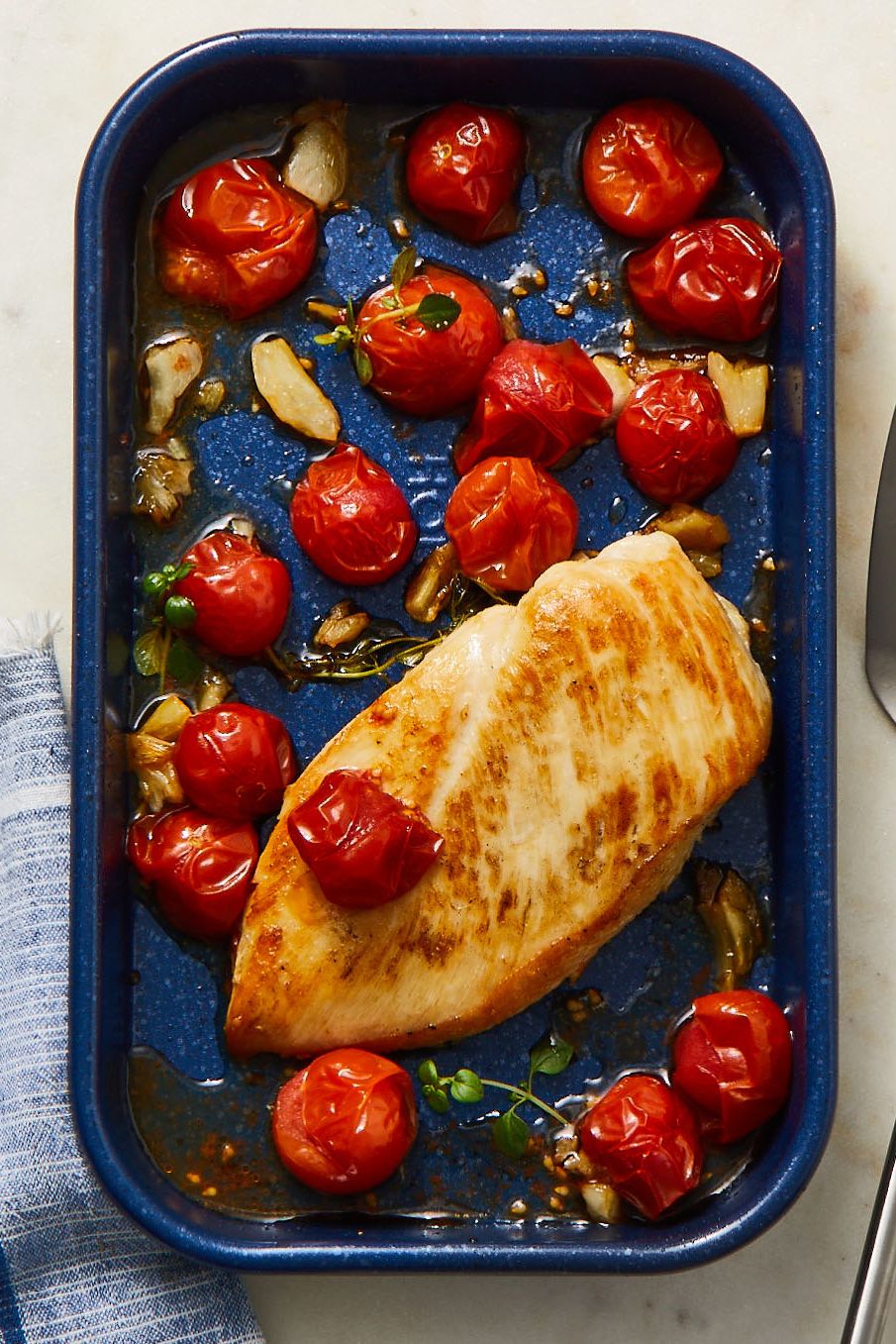 roasted chicken and tomatoes on a blue pan