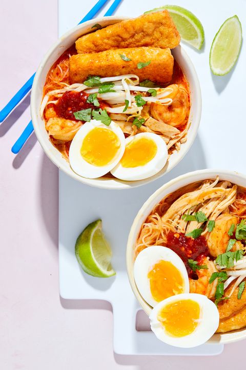 two bowls of chicken curry laksa topped with soft boiled eggs and cilantro