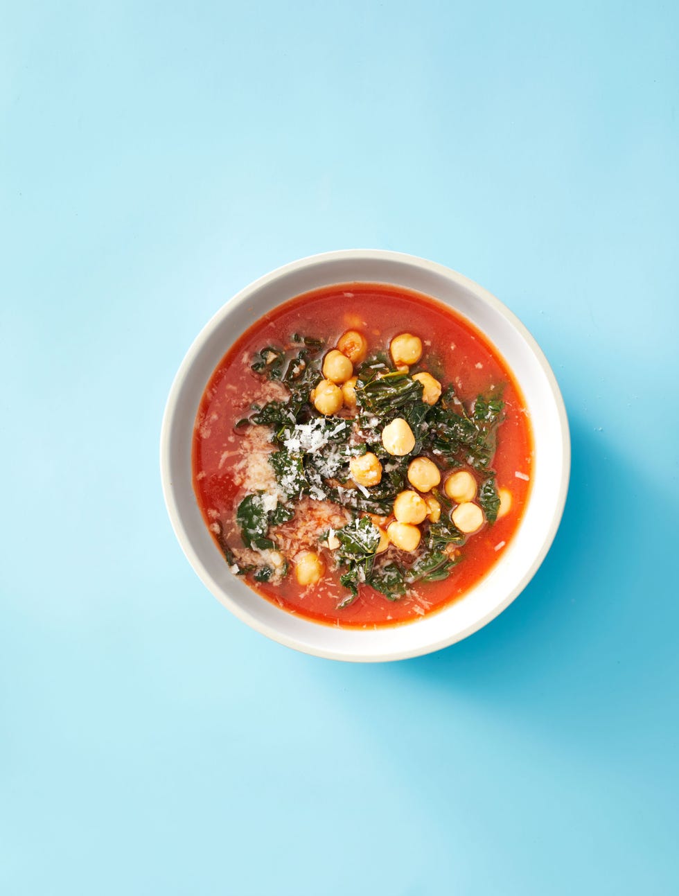 a bowl of kale and chickpea soup against a blue background