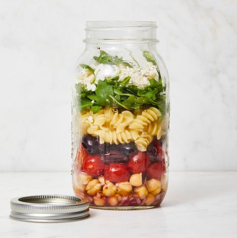 chickpea pasta salad in a jar with tomatoes, olives, red onions, and crumbled feta