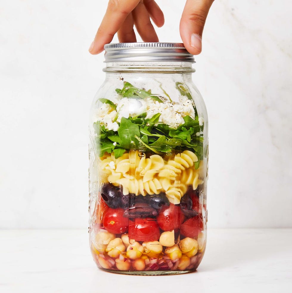 chickpea pasta salad in a jar with tomato, olives, red onion, arugula and cheese