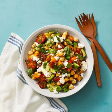 chickpea salad with tomatoes, feta and smashed cucumbers in a white bowl