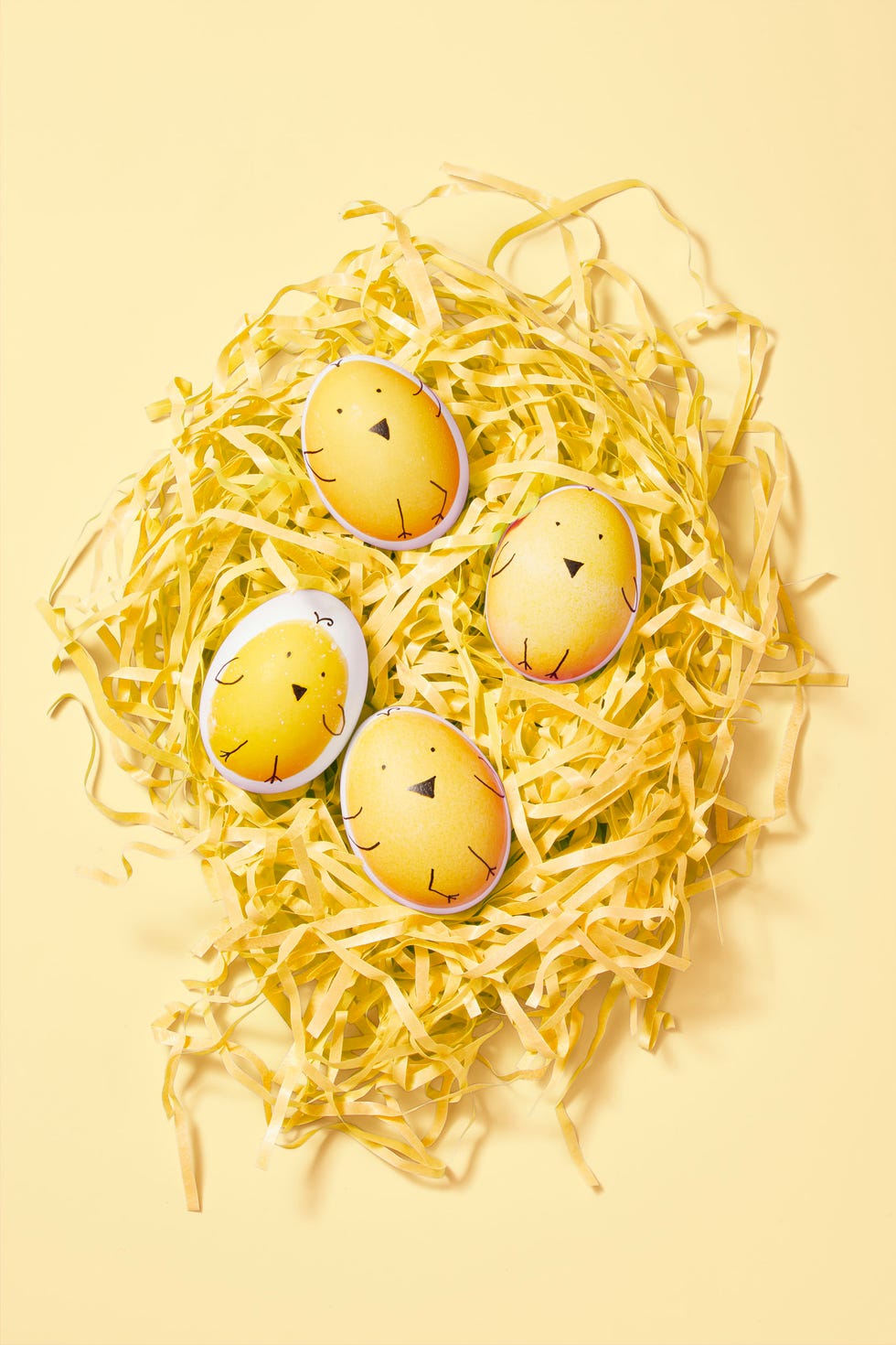 easter egg ideas, eggs painted to look like chicks laying on ripped tissue paper