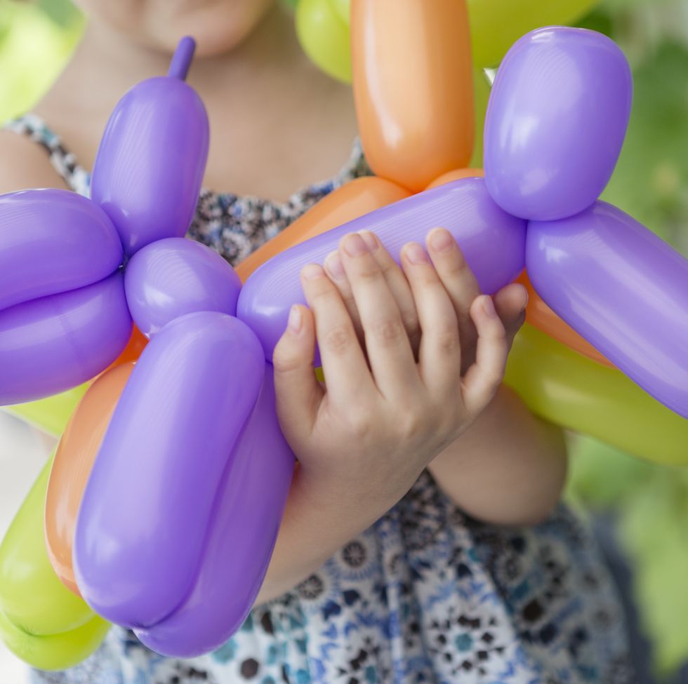 child carrying inflated dog shaped modelling balloons