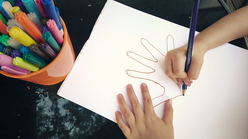 child drawing outline of a hand
