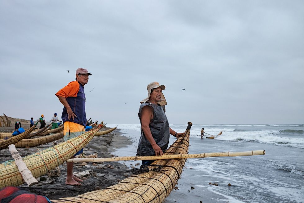 Vissers op Pimentel Beach bereiden zich voor om hun rieten bootjes de Pacifische zee op te laten gaan