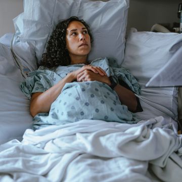 a pregnant woman lies in a hospital bed and speaks with her doctor while in labor