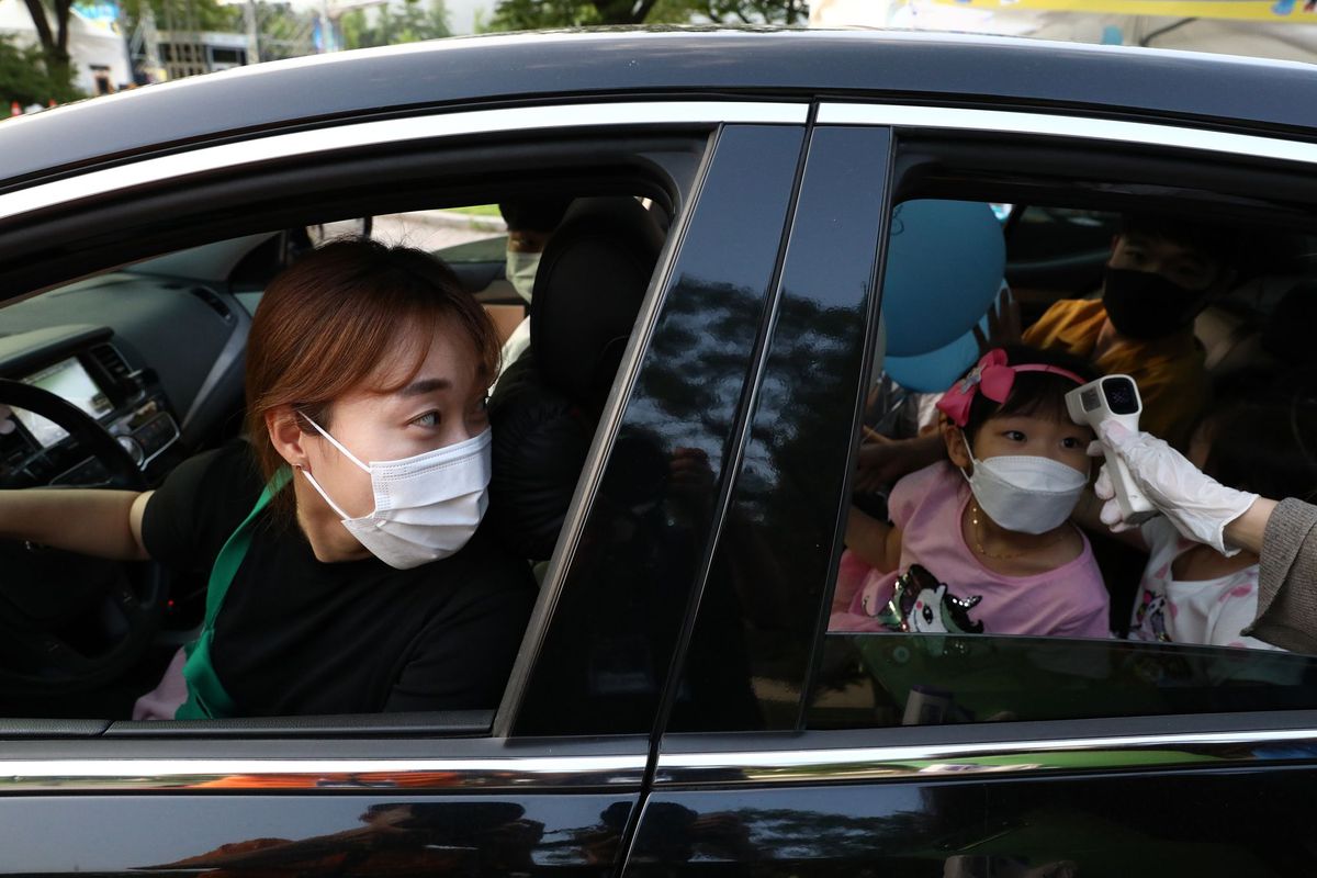 In een driveinkliniek in ZuidKorea kijkt een moeder toe hoe bij haar dochtertje de temperatuur wordt opgenomen Uit een onderzoek onder 65000 mensen dat onlangs door het South Korean Center for Disease Control is gepubliceerd blijkt dat kinderen boven de tien jaar het virus net zo efficint verspreiden als volwassenen