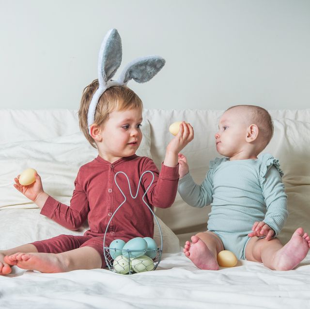 children at home with easter basket on bed. brother and sister find easter eggs
