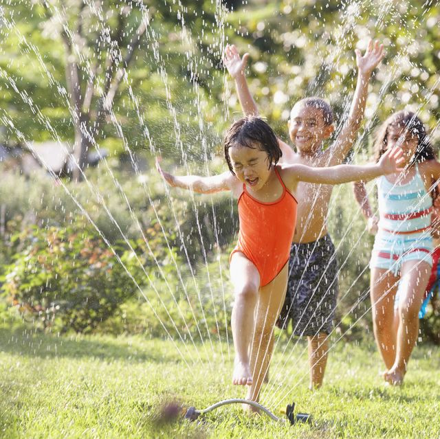 children running through water sprinkler