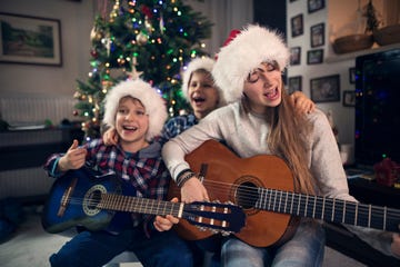niños cantando villancicos delante del árbol