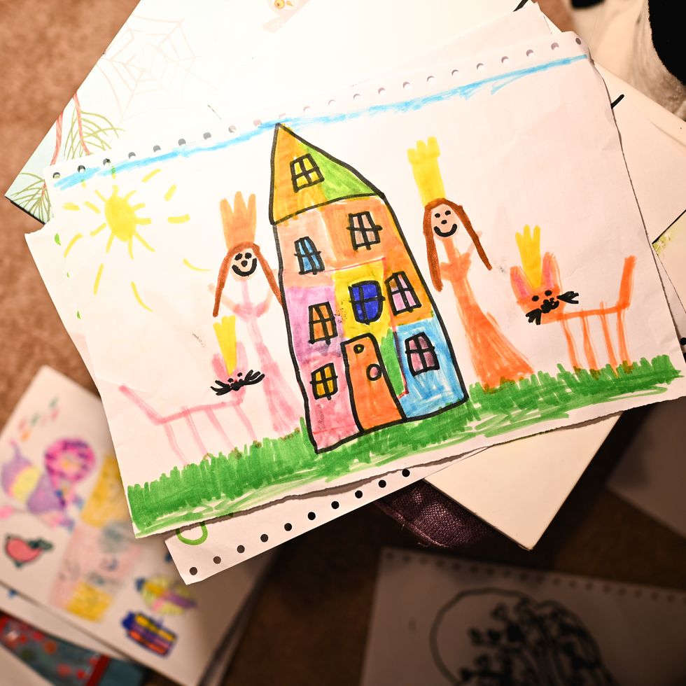 child's drawing of a colorful house, princesses, and a cat under the sun